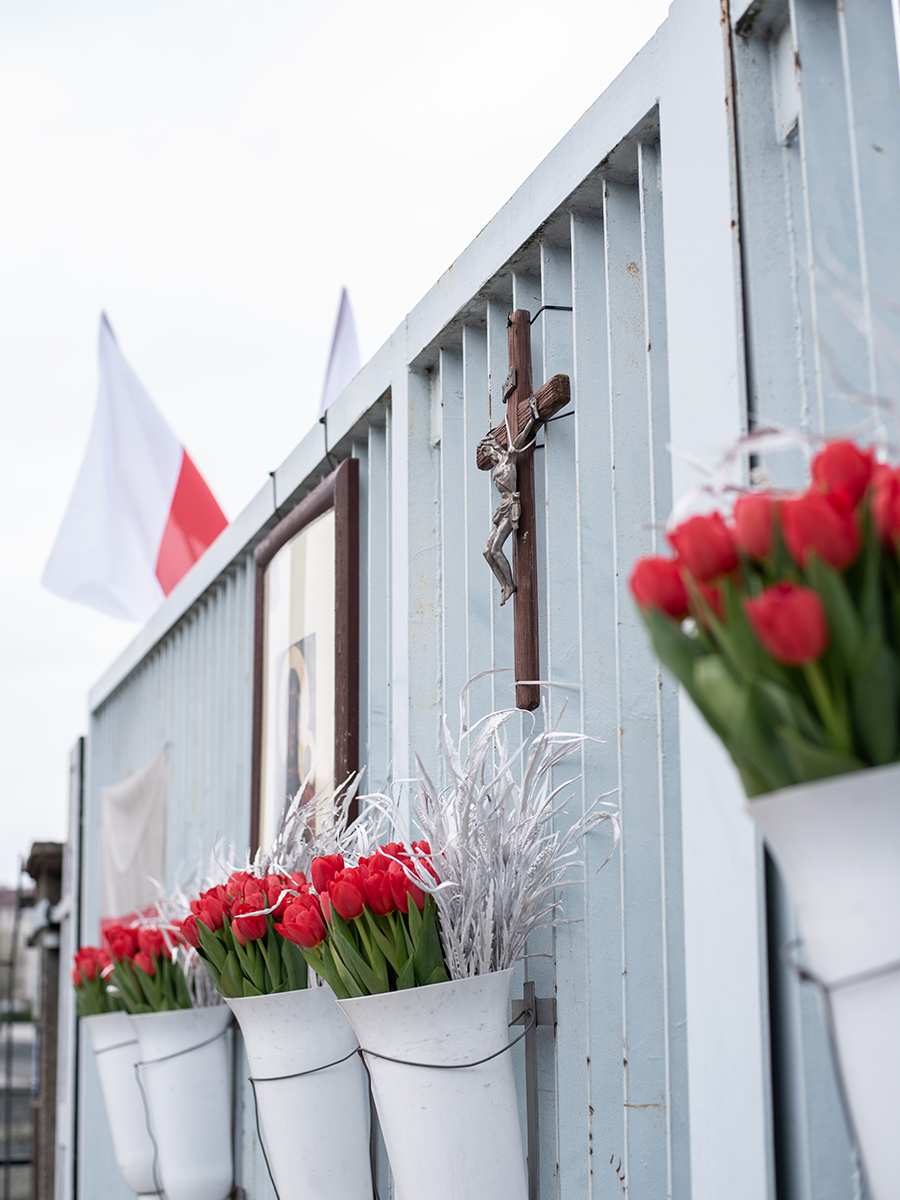 Kreuz mit Jesusfigur und Blumen am Solidarność-Tor in Danzig