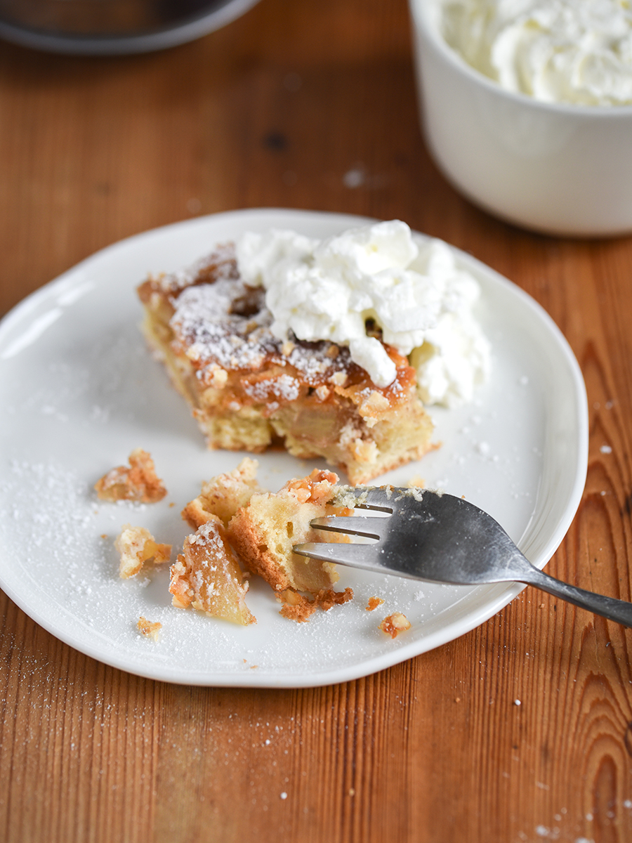 Stück Apfelkuchen mit Marzipan und Mandeln auf einem weißen Teller