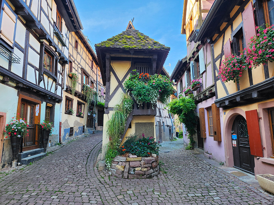 Spitz zulaufende Häuserecke mit Fachwerk und Blumenschmuck in Eguisheim
