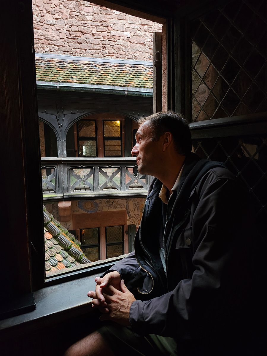 Mann sitzt am Fenster in der Hohkönigsburg und blickt hinaus in den Burghof