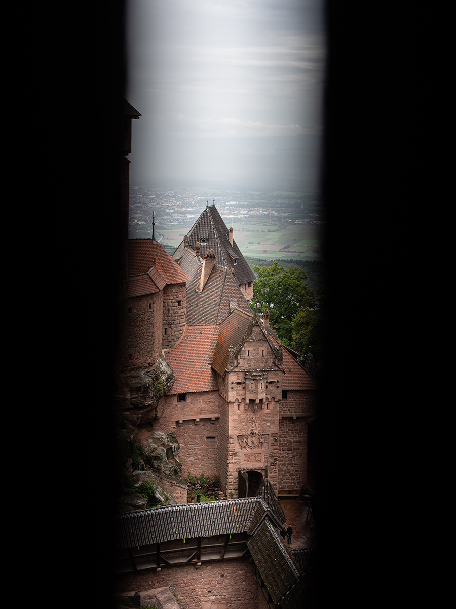 Aussicht durch eine Schießscharte der Hohkönigsburg auf die Dächer und das Tal