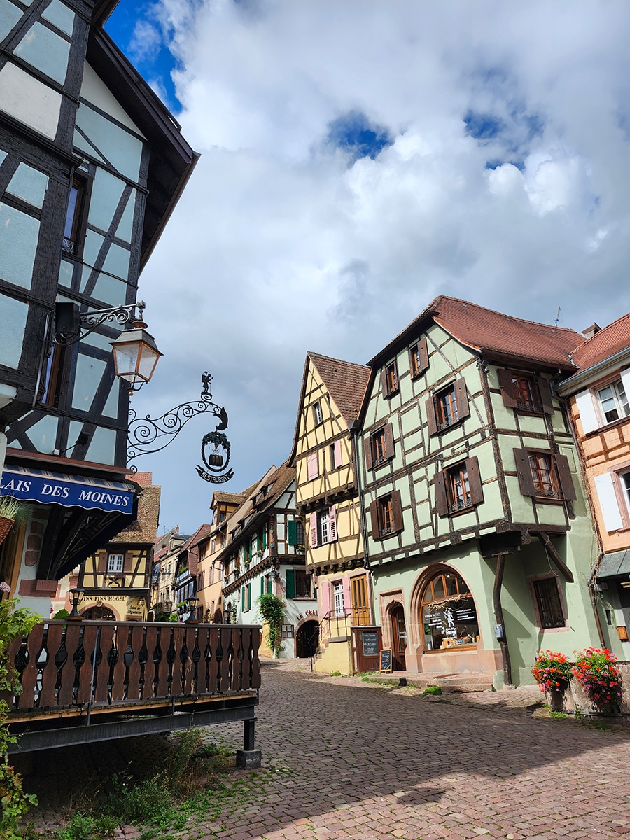 Fachwerkhäuser mit Weinranken und Blumenschmuck in Riquewihr, Elsass