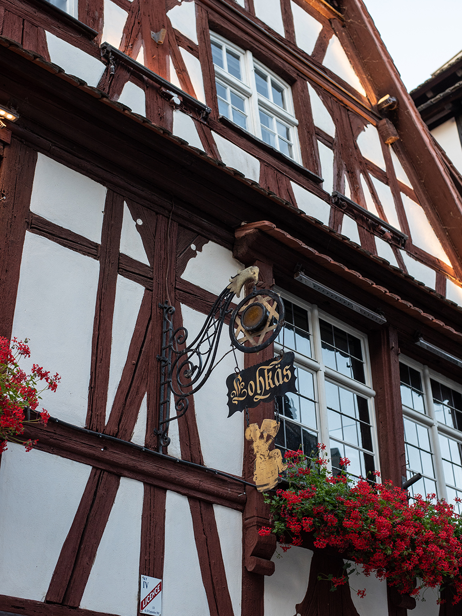 Traditionelles Fachwerkhaus in Straßburg mit Gasthaus-Schild „Lohkäs“ und Blumenschmuck