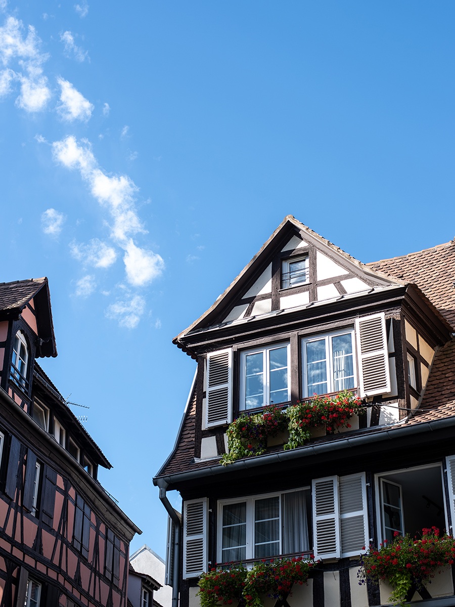 Traditionelles Fachwerkhaus in Straßburg mit weißen Fensterläden und Blumenkästen