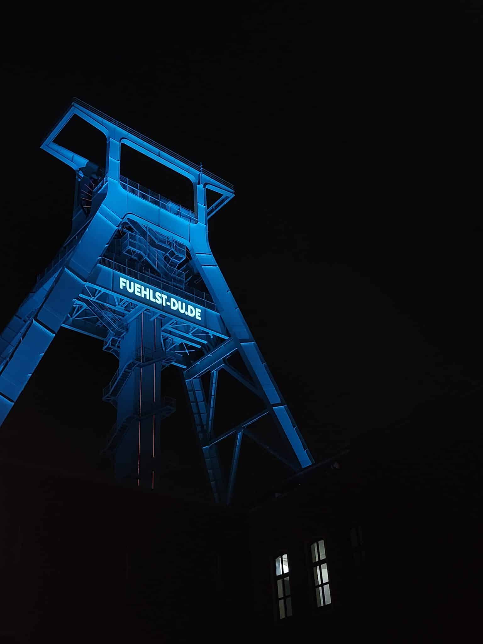 Blau beleuchteter Förderturm des Deutschen Bergbau-Museums Bochum bei Nacht