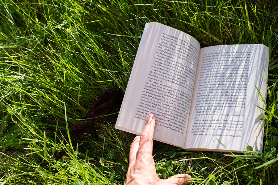 Aufgeschlagenes Buch „Im Wasser sind wir schwerelos“ liegt auf grünem Gras