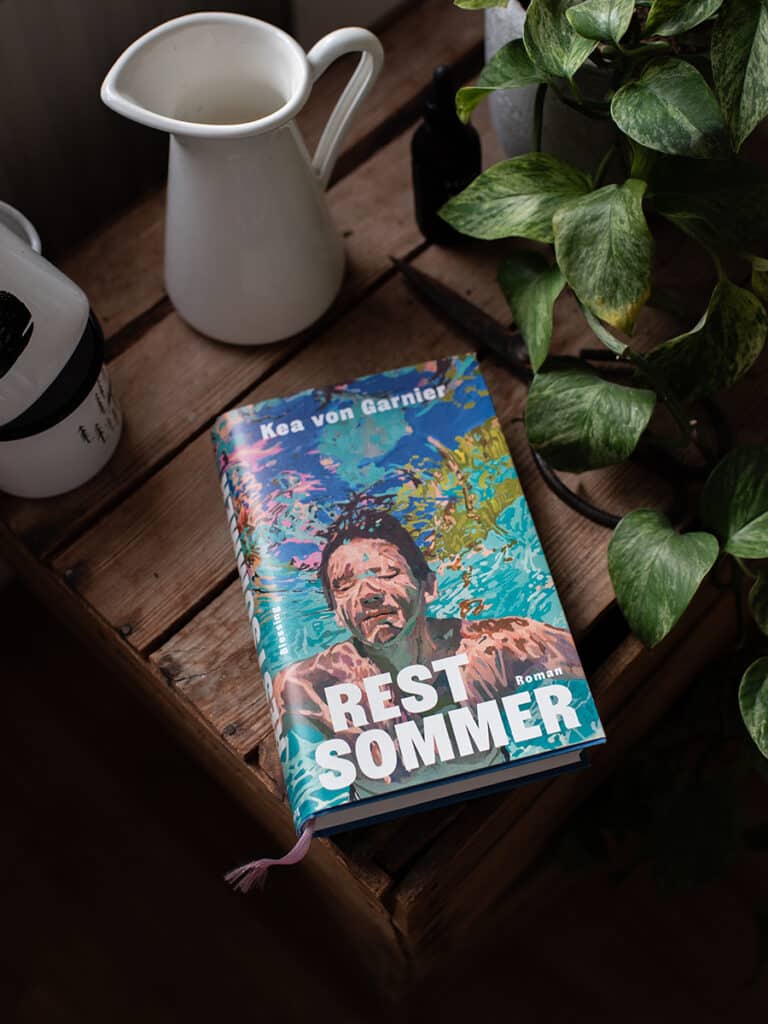 Buch „Restsommer“ von Kea von Garnier auf einem Tisch neben einer Tasse und einer Pflanze