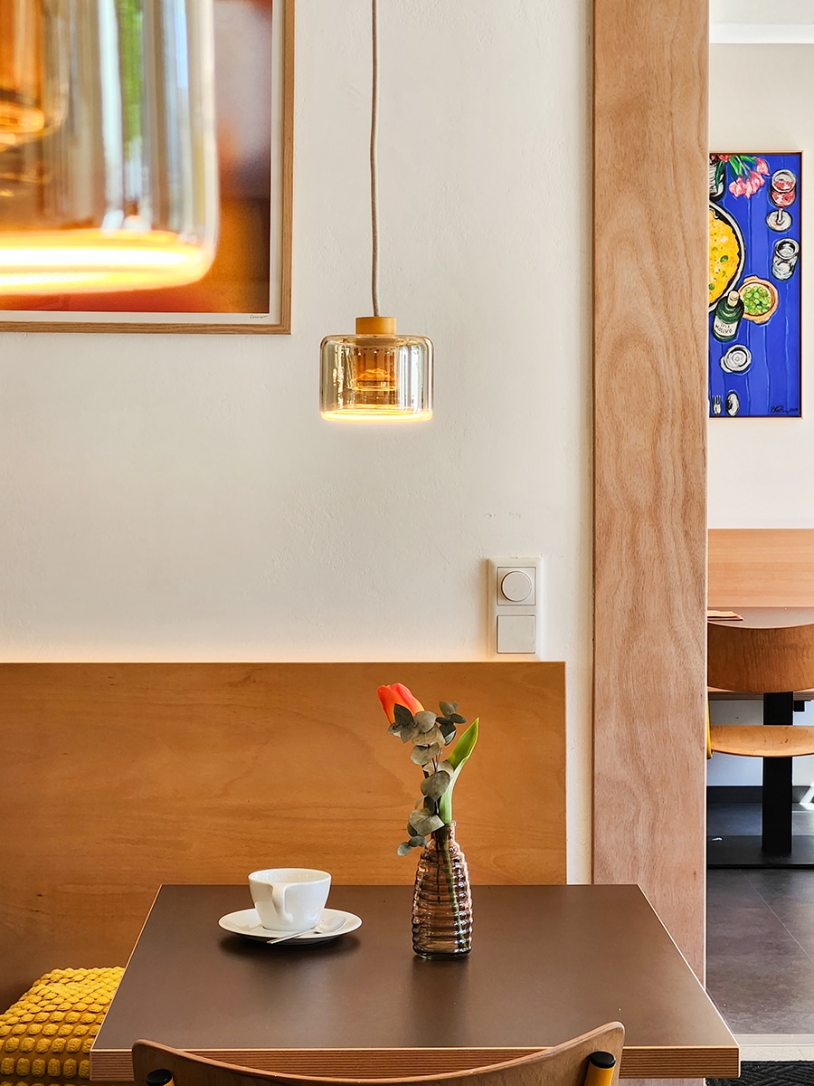 Tisch im Heinrichs in Paderborn mit einzelner Blume, Holzbänken und gelben Akzenten im Hintergrund