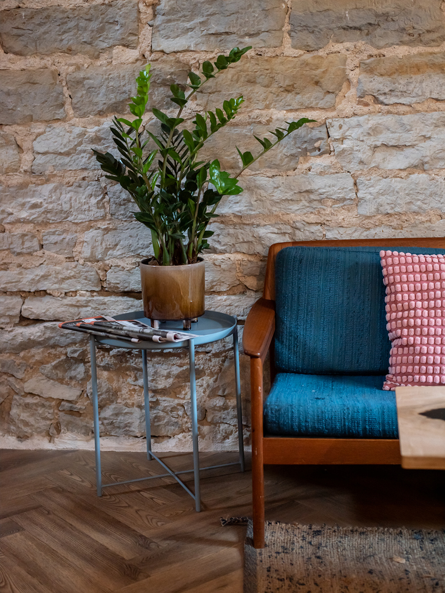 Sitzecke im Kiosk No. 4 in Tallinn mit blauem Sessel, Pflanze und Natursteinwand
