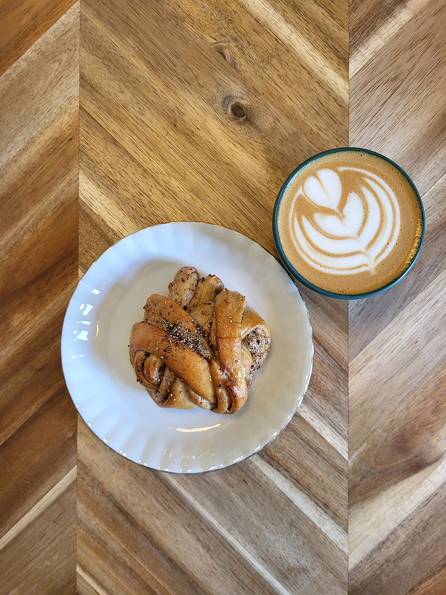Cappuccino mit Latte Art und Gebäck auf einem Holztisch im Kiosk No. 4 in Tallinn