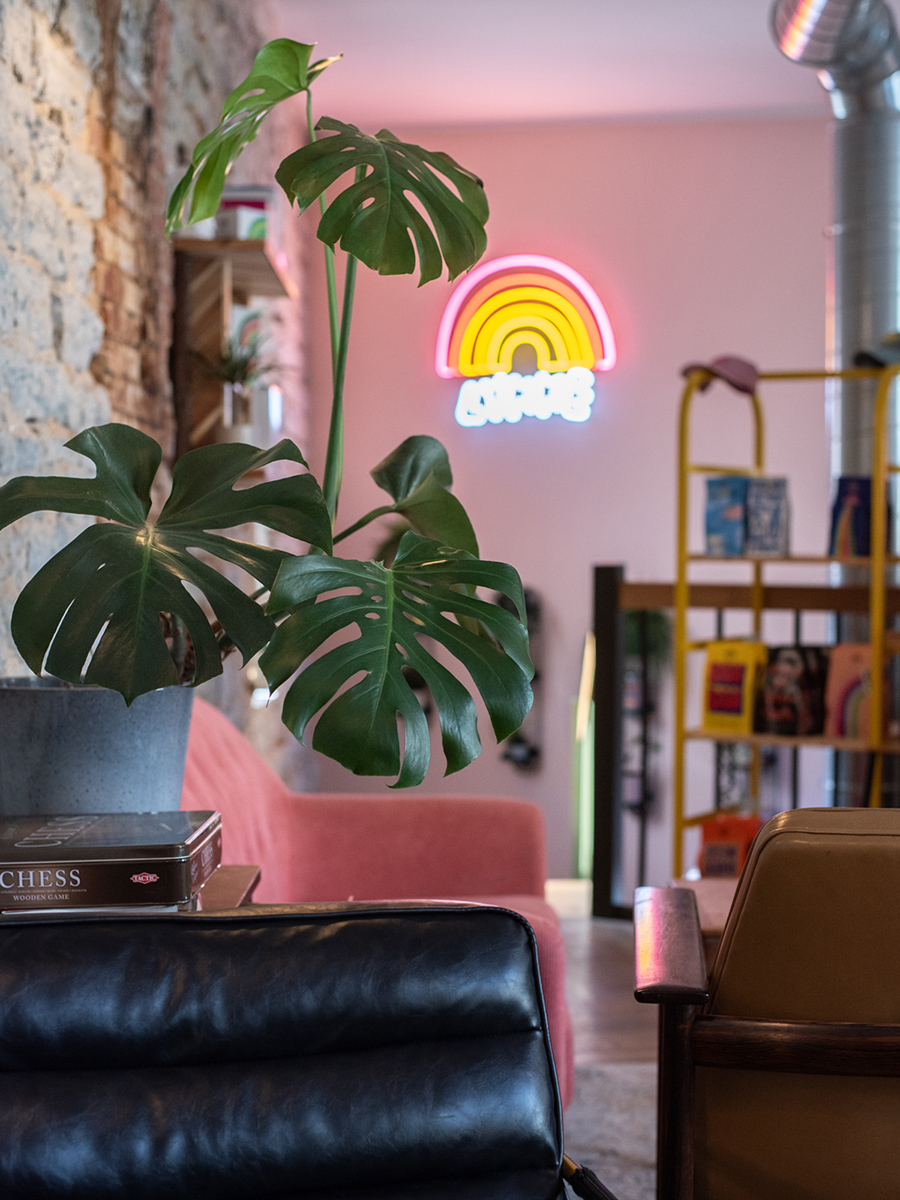 Innenraum des Kiosk No. 4 in Tallinn mit großer Monstera, schwarzem Ledersofa und Neonlicht