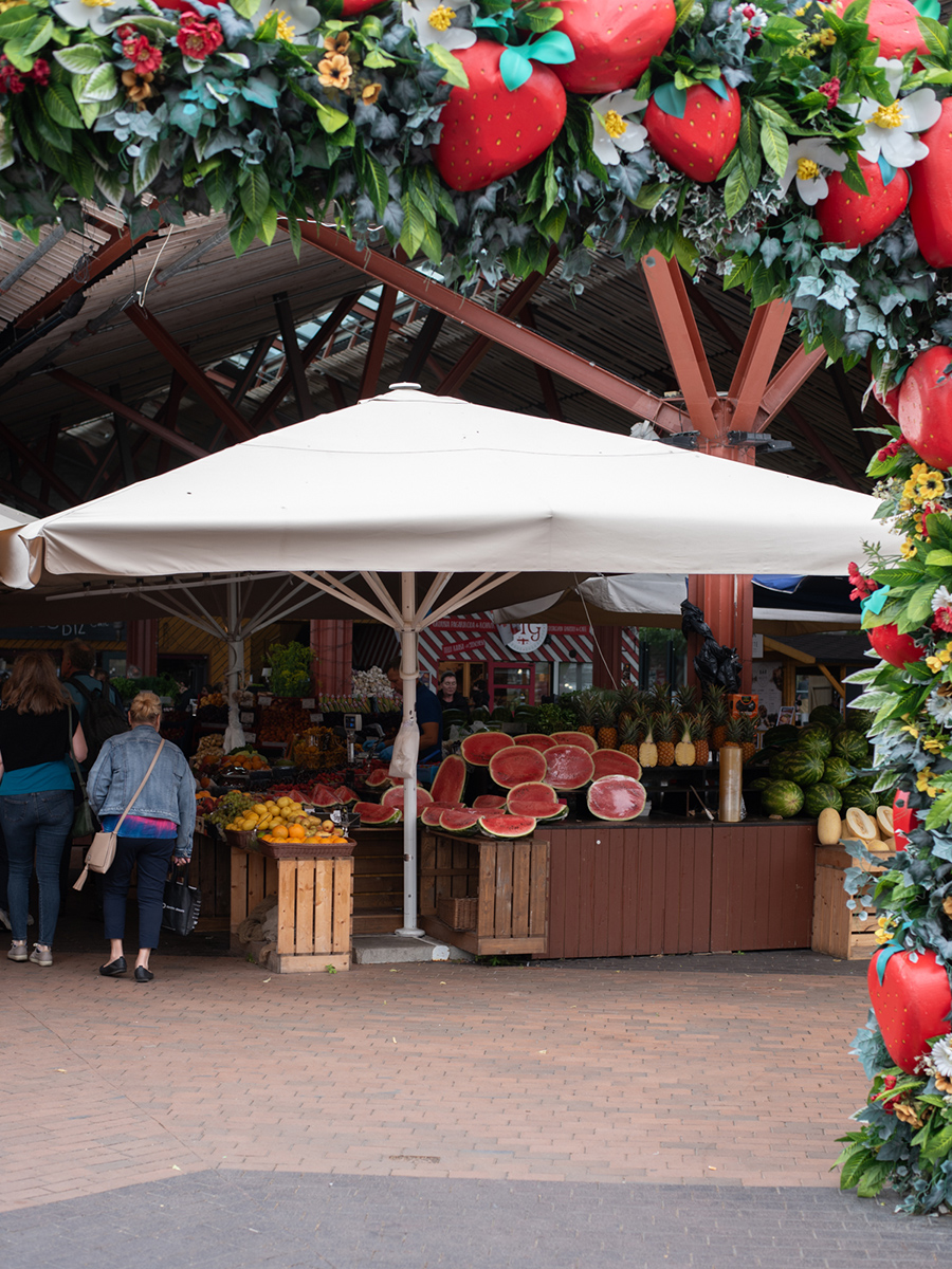 Marktstand mit Waren unter Sonnenschirmen vor dem Balti Jaama Turg in Tallinn