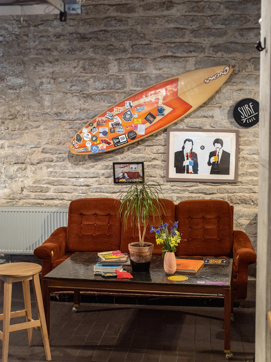 Sitzbereich des Surf Café im Balti Jaama Turg in Tallinn mit Surfbrett an der Backsteinwand