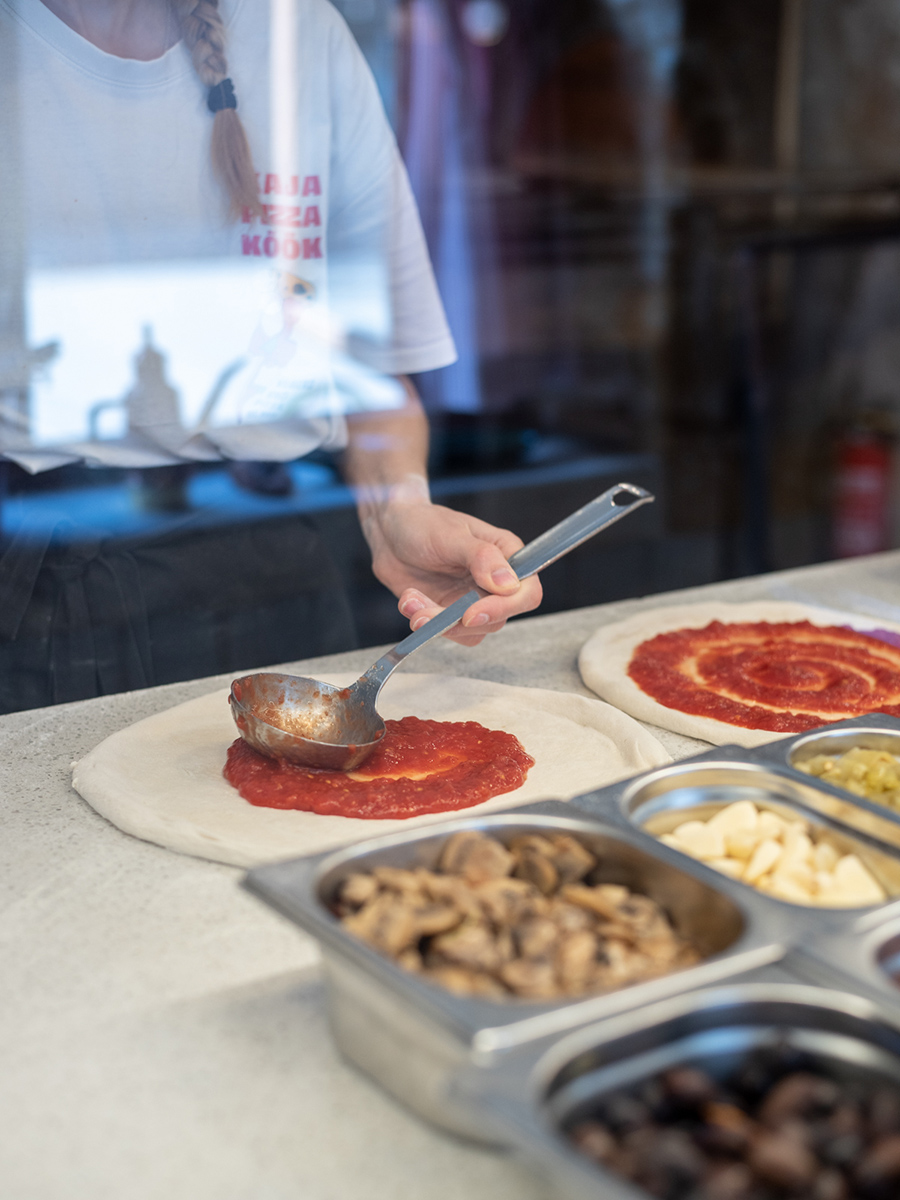 Zubereitung einer neapolitanischen Pizza mit Tomatensauce und frischen Zutaten im Kaja Pizza Köök in Tallinn