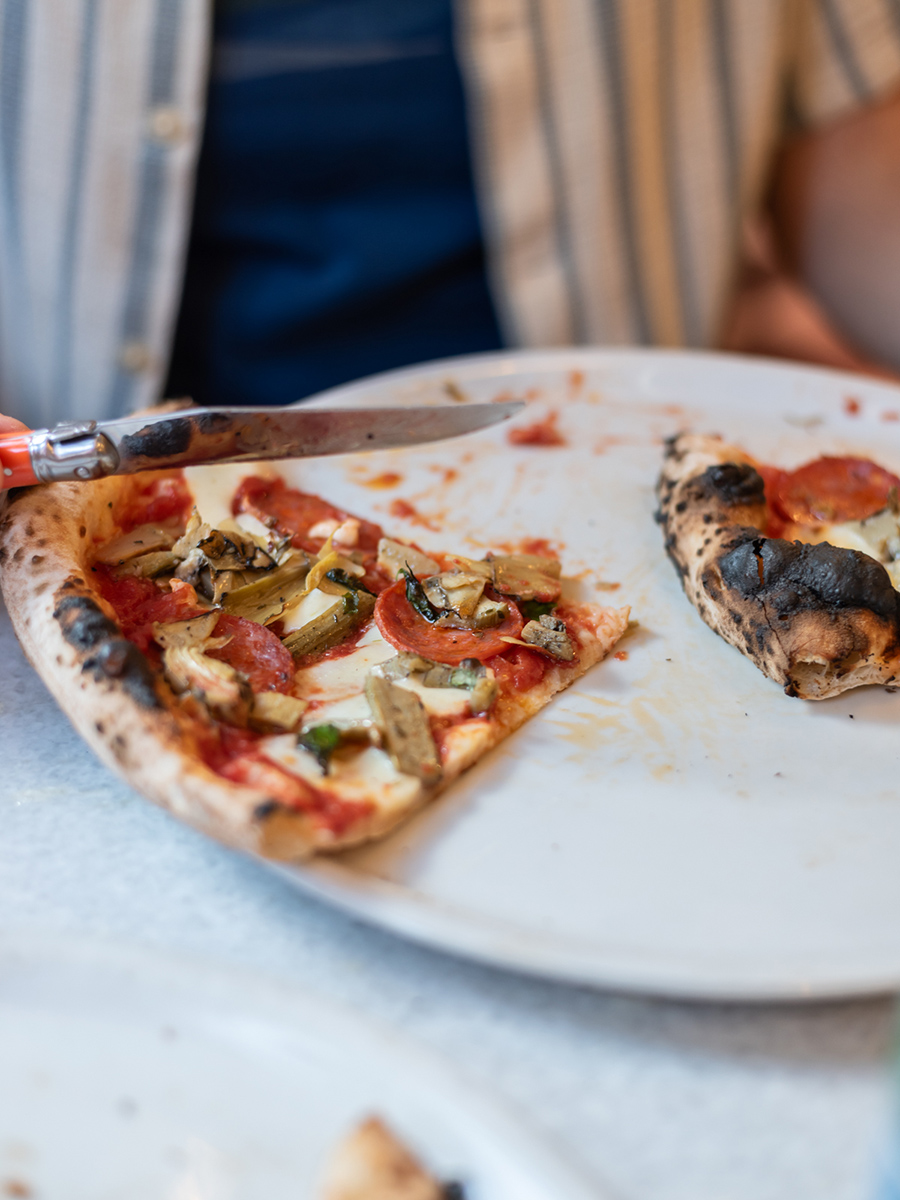 Angeschnittene neapolitanische Pizza mit Gemüse auf einem weißen Teller im Kaja Pizza Köök in Tallinn