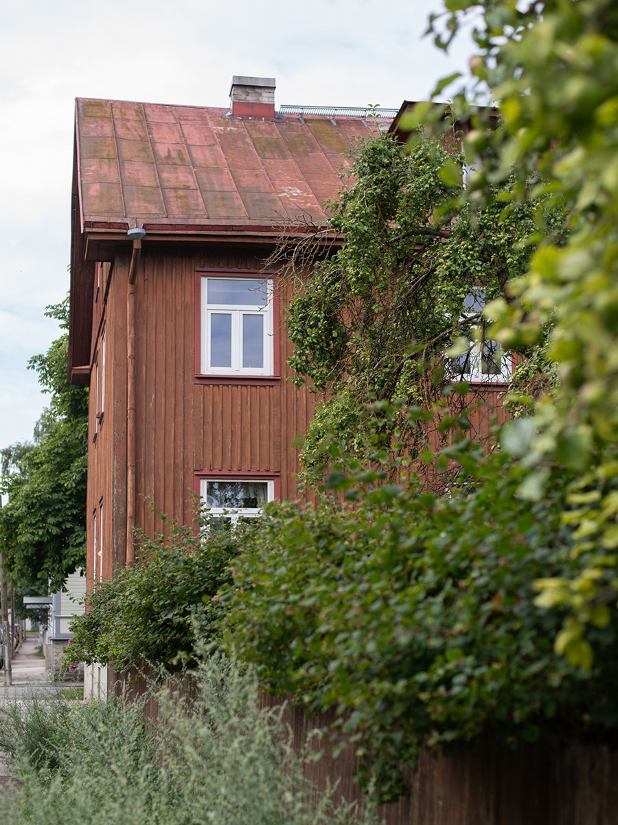 Rotes historisches Holzhaus hinter Bäumen und Sträuchern im Tallinner Stadtteil Kalamaja