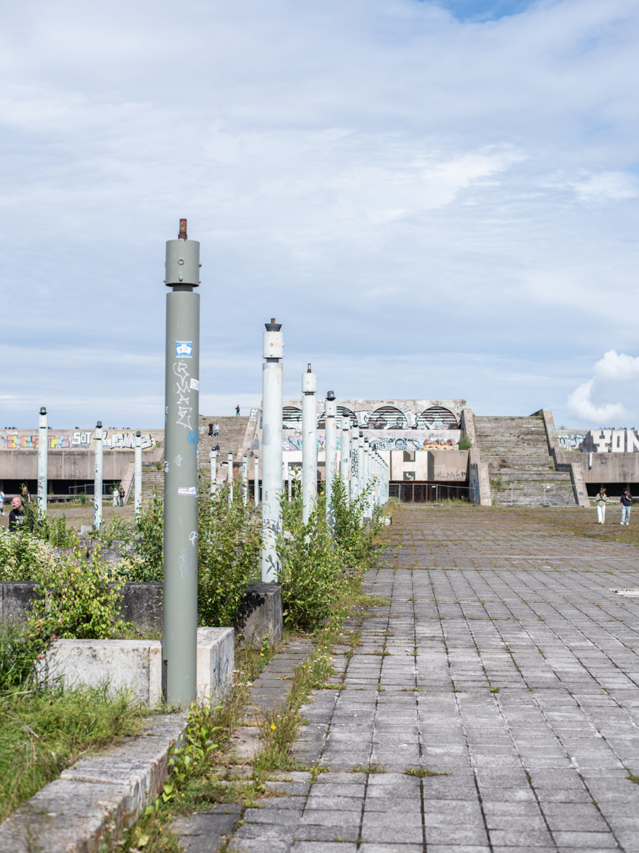 Verwitterter Betonweg auf der Linnahall in Tallinn mit Pflanzen und Hafen im Hintergrund