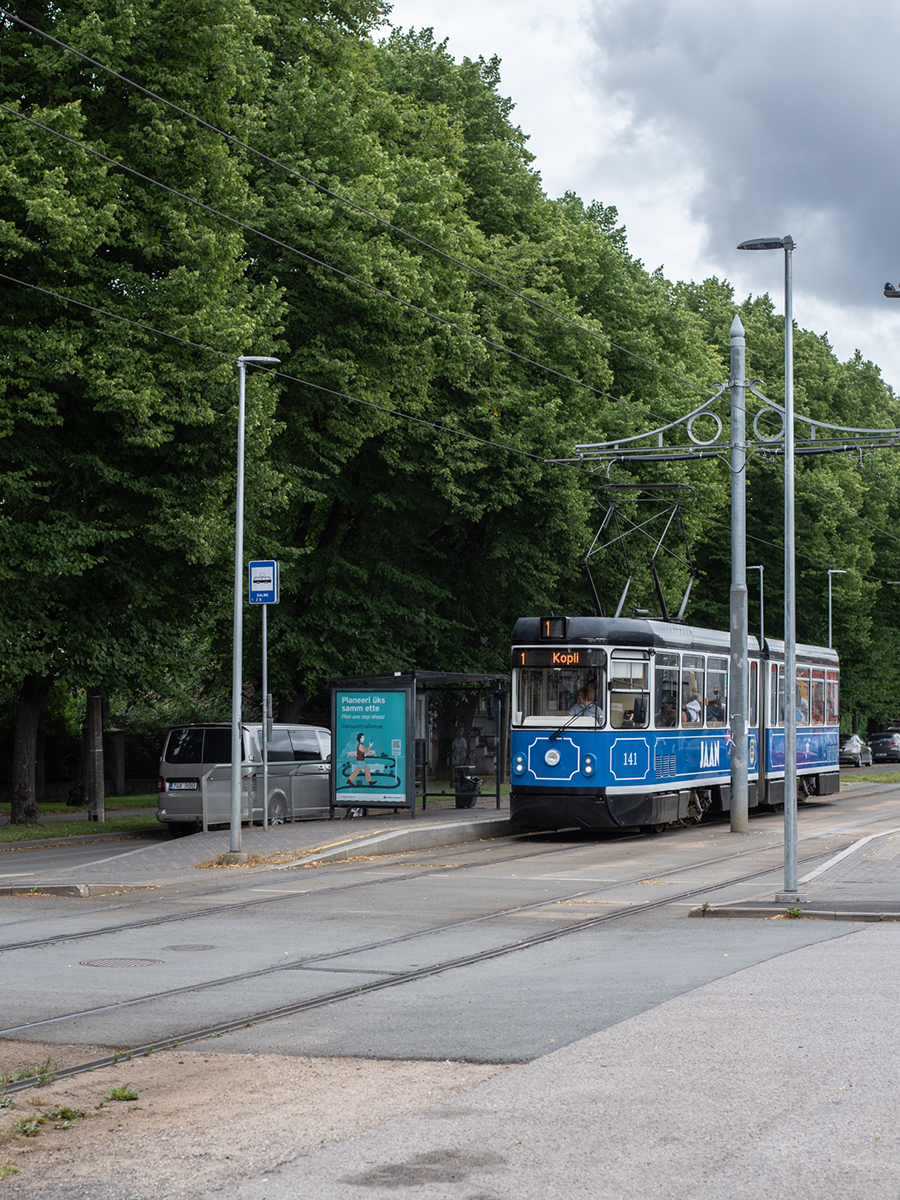 Blaue Straßenbahn auf einer von Bäumen gesäumten Strecke in Tallinn