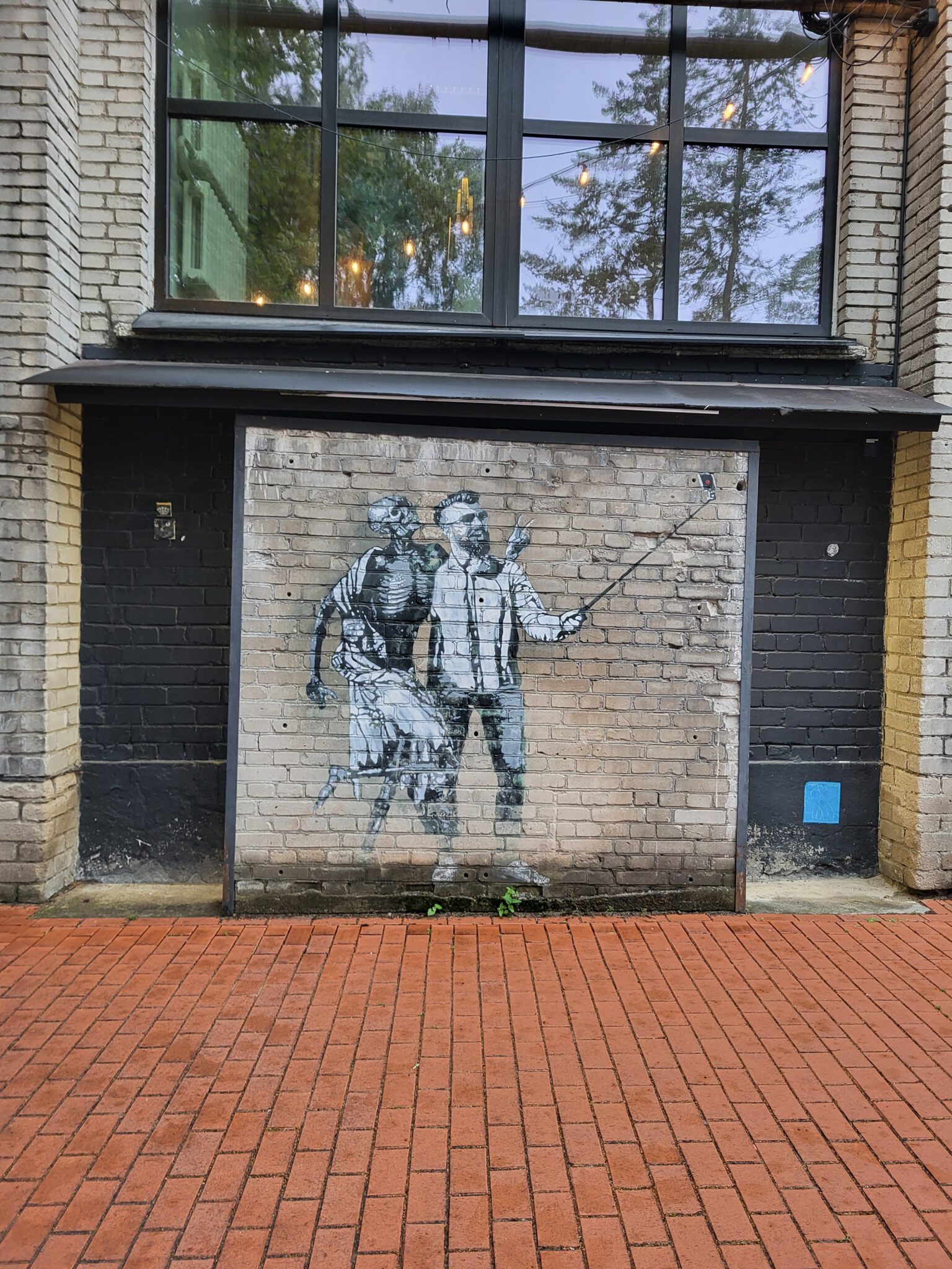 Schwarz-weiße Street-Art mit einer menschlichen Figur an einer Backsteinwand in Telliskivi